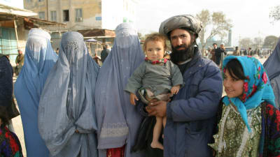 En familj i Afghanistans huvudstad Kabul. pappan i familjen har det yngsta barnet i famnen. Kvinnorna är klädda i burka.