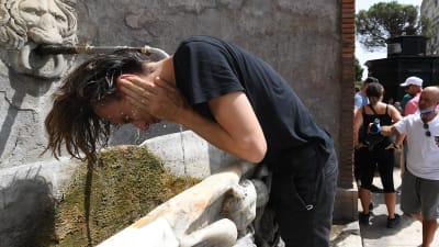 Någon skvättar vatten på sig vid en drickfontän i Rom i Italien.