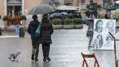 Ett påar promenerar i regnet i Rom