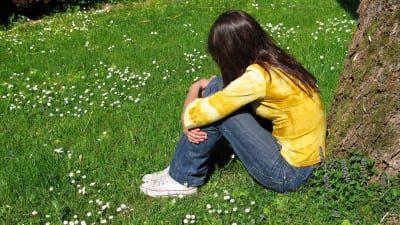 Ung kvinna sittande på gräsmatta.