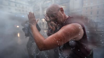 Man blir beskjuten med vattenkanon i ansiktet under en demonstration.