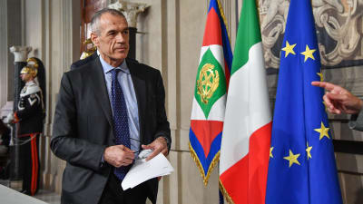 Carlo Cottarelli vid den italienska och EU-flaggan. 