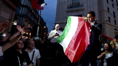 Femstjärnerörelsens Luigi di Maio håller upp den italienska flaggan under ett möte med anhängare i Neapel.