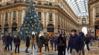 Julshopping i Milan. På bild flera människor i en köphall. I mitten står en stor julgran.
