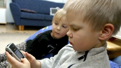 Två pojkar tittar på en mobiltelefon