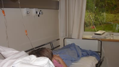 En ungdom som ligger i en sjukhussäng på barnavdelningen.