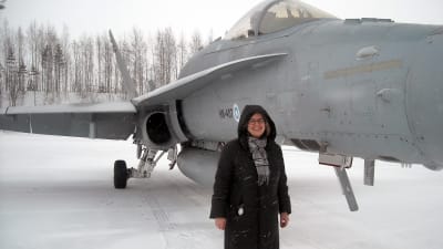 Svenska Yles reporter Kerstin Kronvall framför en F-18 Hornet i Rissala.