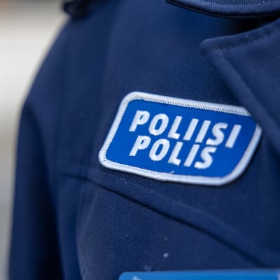 Ett tygmärke med texten Poliisi Polis på en blå uniform.