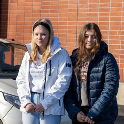 Lempääläläinen Miia Järvinen ja vesilahtelainen Anniina Kolu poseeraamassa mopoauton edessä Lempäälän lukion parkkipaikalla.