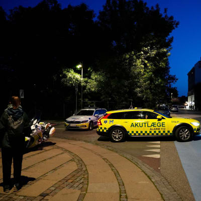 En polisbil står på tvären på en gata i ett kvällsmörkt Köpenhamn. 