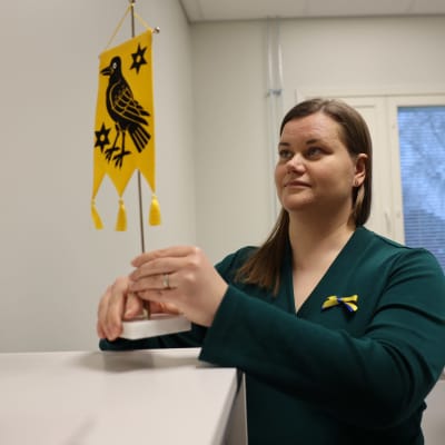 Kunnanjohtaja Satu Simelius asettelee Sauvon vaakunaviiriä työhuoneensa arkistokaapin päälle.