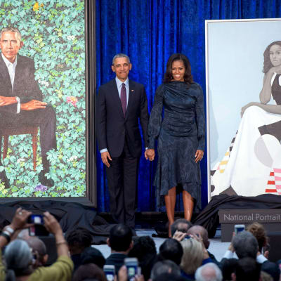 Barack och Michelle Obama poserar bredvid sina porträtt