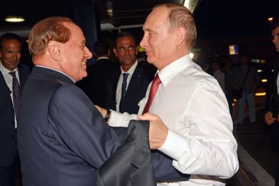 Silvio Berlusconi och Vladimir putin ler mot varandra, Berlusconi ser ut att omfamna Putin.