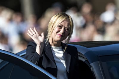 Kvinnlig politiker vinkar framför svart bil