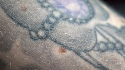 Lähikuvassa tatuoitu kyynärvarsi, jossa näkyy luomia.