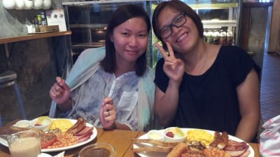 Två kinesiska kvinnor på en restaurang. På tallrikarna har de en traditionell english breakfast.
