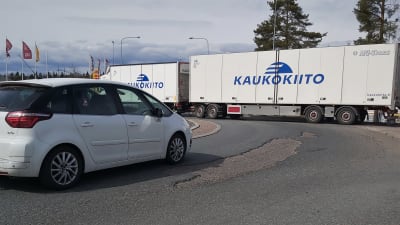 Personbil och långtradare i en rondell med sprickor i asfalten