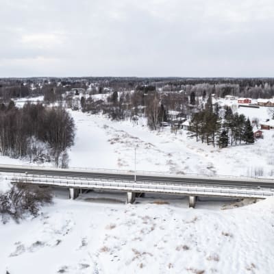 Kaakamojoen silta Torniossa.  Joki on jäässä ja maisema luminen. Taustalla näkyy omakotitaloja.