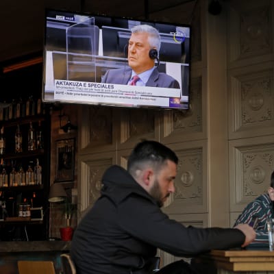 Miehet istuvat baarissa Pristinassa ja Kosovon ex-presidentin oikeudenkäynti on meneillään telkkarissa