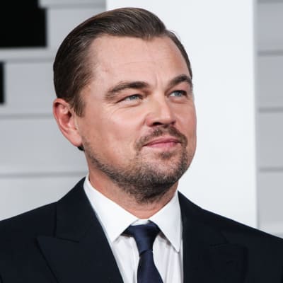 Leonardo DiCaprio i mörk kostym och vit skjorta tittar åt sidan och höjer något på ögonbrynen.