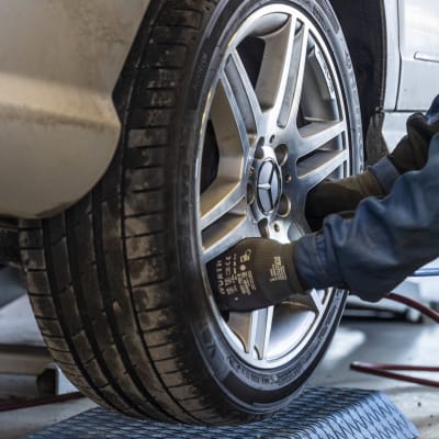 Tornion Lapin Kumin työntekijä vaihtavat kesärenkaita autoon.