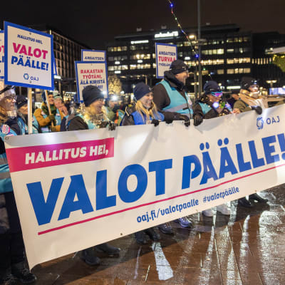 Ihmisjoukko torilla pitelee kylttejä käsissään.
