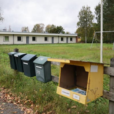 Postilaatikkorivistö tyhjenneen rivitalon pihalla.
