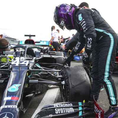 Lewis Hamilton inspekterar sitt trasiga däck.