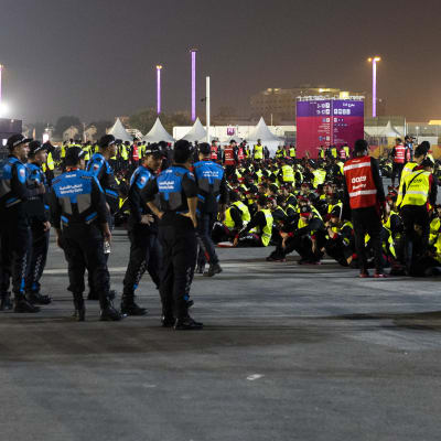 Stadium 974. Poliisit valvovat jalkapallon mm-kisojen työntekijöitä 18.11.2022 illalla stadionin ulkopuolella.