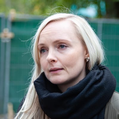 Ljushårig kvinna mot en grön bakgrund. Inrikesminister Maria Ohisalo (Gröna)