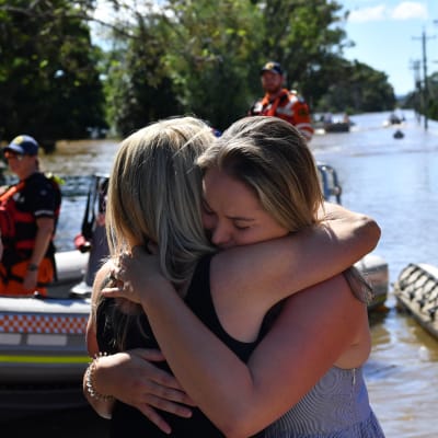 En mamma och dotter kramas då de återförenats efter att ha evakuerat undan översvämningar i Australien