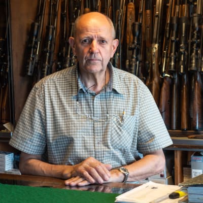 Porträtt på vapenhandlaren William Wadstein. Han står framför flera vapen i sin affär.