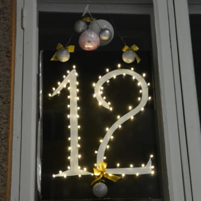 Numret 12 är smyckat med julgransbollar i ett husfönster.