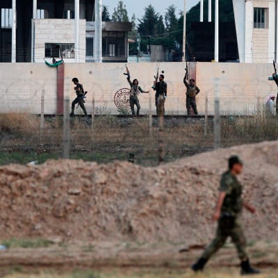 Soldater i Fria syriska armén i bakgrunden, fotograferade från den turkiska sidan av gränsen mellan länderna.
