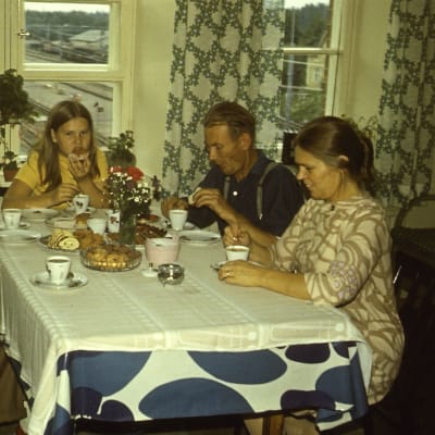 Familj som fikar, på kläder och inredning ser man att det är 1970-talet.