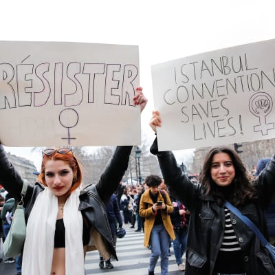 Två demonstranter i Paris håller skyltar med orden "Motstånd" och "Istanbulkonventionen räddar liv" 