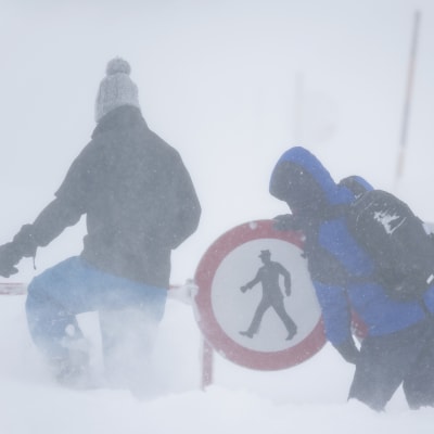 Fotgängare putsar en nedsnöad vägskylt i Arlberg.