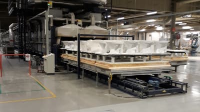 Ett antal wc-stolar uppradade framför en lång förbränningsugn på en fabrik.