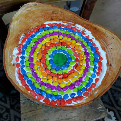 Mosaikstenar i olika färger limmade på en stubbe