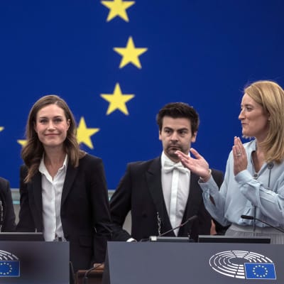 Sanna Marin (sd.) hymyilee EU-parlamentissa, parlamentin puhemies Roberta Metsola taputtaa vieressä. 