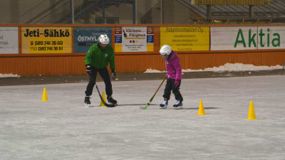 En tjej tränar på att dribbla mellan gula koner på isen. 