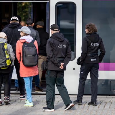 Biljettkontollanter köar för att stiga på ett tåg. 