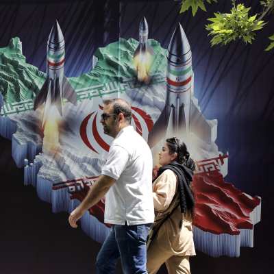 Ett iranskt par går förbi en väggmålning med iranska raketer.