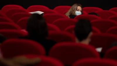En kvinna omgiven av röda sammetsstolar i en biograf.