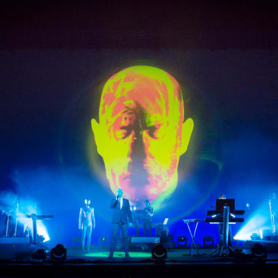 Pet Shop Boys lavalla, taustalla iso valaistu pää.