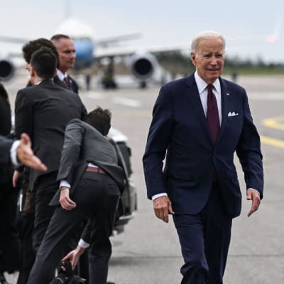 Joe Biden kävelee lentokentällä. Taustalla lentokone.