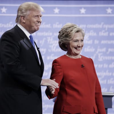 Donald Trump ja Hillary Clinton kättelevät ja hymyilevät.