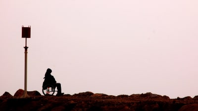 Ensam person i rullstol vid havet. 