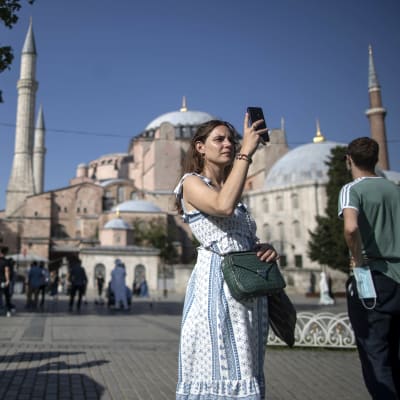 Nainen ottaa kuvaa puhelimella Hagia Sofian moskeijan edessä Istanbulissa.