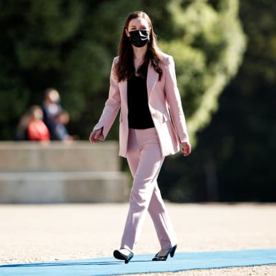 Statsminister Sanna Marin går utomhus iklädd en rosa kostym.